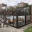 Foto Modernes, zweistöckiges Pop-up-Restaurant aus schwarzen Containern mit verglastem Erdgeschoss, einer sichtbaren Küche im Innenraum und einer voll besetzten Dachterrasse mit Holzverkleidung in einer urbanen Parkanlage.