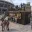 Foto Ein anthrazitfarbener 20-Fuß-Seecontainer mit Dachterrasse, Bar-Ausschank und „Terra Nova“ Branding auf einem modernen Vorplatz vor einem Fußballstadion. Menschen interagieren im Außenbereich und auf dem Oberdeck.
