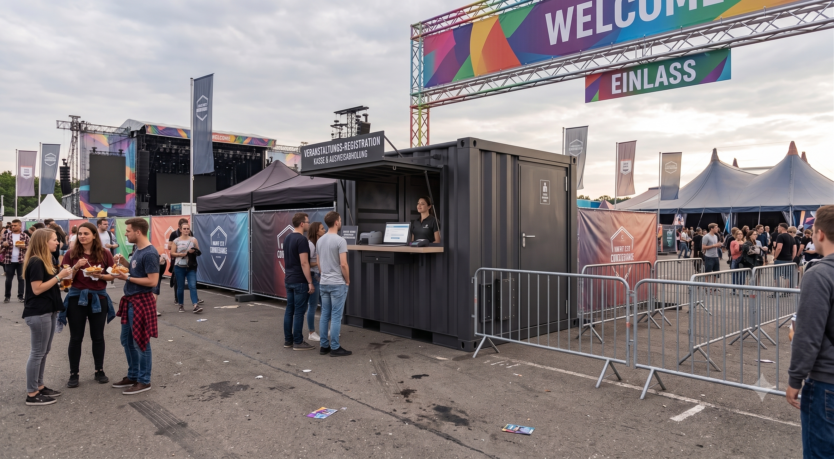 Anthrazitfarbener Kassen- und Registrierungscontainer aus Übersee-Bauteilen auf einem Event-Einlassbereich mit geöffneter Verkaufsklappe, Counter-Arbeitsplatz für das Personal und vorgelagerten Absperrgittern unter einem Welcome-Schild.