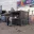 Foto Anthrazitfarbener Kassen- und Registrierungscontainer aus Übersee-Bauteilen auf einem Event-Einlassbereich mit geöffneter Verkaufsklappe, Counter-Arbeitsplatz für das Personal und vorgelagerten Absperrgittern unter einem Welcome-Schild.